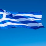 Greek flag waving against blue sky background.